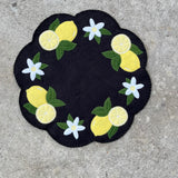 A felt candle mat with lemons and flowers made using an embroidery design from Snugglepuppyapplique.com