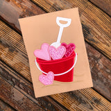 An applique of a bucket full of hearts and a shovel by snugglepuppyapplique.com