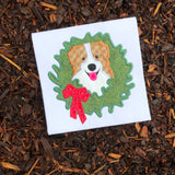 An applique of an Australian Shepherd dog with his head  through a Christmas wreath by snugglepuppyapplique.com