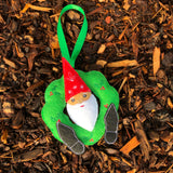 An in the hoop machine embroidery design of a gnome with is head through a holiday wreath and his feet sticking out. by snugglepuppyapplique.com
