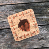 An in the hoop Autumn Coaster with an Acorn in  the center and a boarder of twigs and fall leaves by snugglepuppyapplique.com