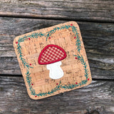 In the hoop Winter coaster with mushroom in the center and a border of evergreen boughs and berries by snugglepuppyapplique.com