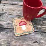 In the hoop Winter coaster with mushroom in the center and a border of evergreen boughs and berries by snugglepuppyapplique.com  Edit alt text