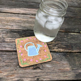 An in the hoop spring coaster with a watering can in the center and a boarder of tulips by snugglepuppyapplique.com