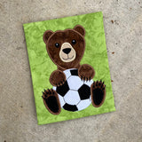Bear mascot holding a soccer ball applique embroidery design by snugglepuppyapplique.com