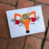 An applique of a fox face wearing a crown of Autumn foliage, sunflower, acorn and leaves by snugglepuppyapplique.com