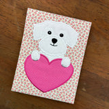A valentine applique of a Maltese dog with its paws on a heart shape by snugglepuppyapplique.com