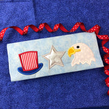 An applique of Uncle Sam's top hat, a five pointed star and bald eagle head  by snugglepuppyapplique.com