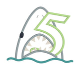 An applique of a shark biting the number five by snugglepuppyapplique.com