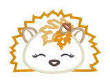 An applique of a sleeping hedgehog with fall leaves and an acorn by snugglepuppyapplique.com  Edit alt text