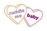 An applique of candy hearts with the words "cuddle me" and "baby" embroidered on them by snugglepuppyapplique.com