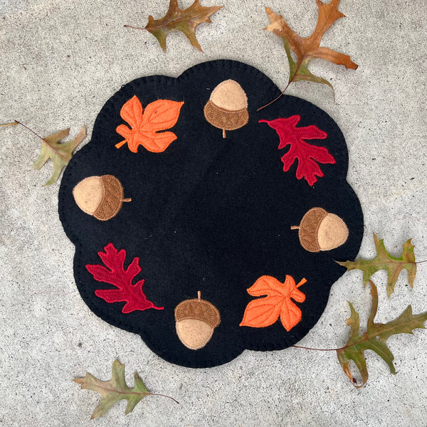An in the hoop candle mat with acorns and fall leaves embroidery design by snugglepuppyapplique.com