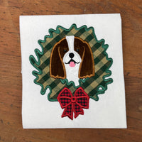 An applique of a Cavalier King Charles Spaniel with its head through a Christmas wreath in 6 sizes by snugglepuppyapplique.com
