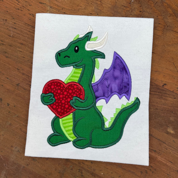 An applique of a Dragon holding a heart shape for Valentines day by snugglepuppyapplique.com