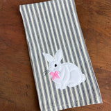 An applique of a white rabbit with a ribbon bow attached by snugglepuppyapplique.com
