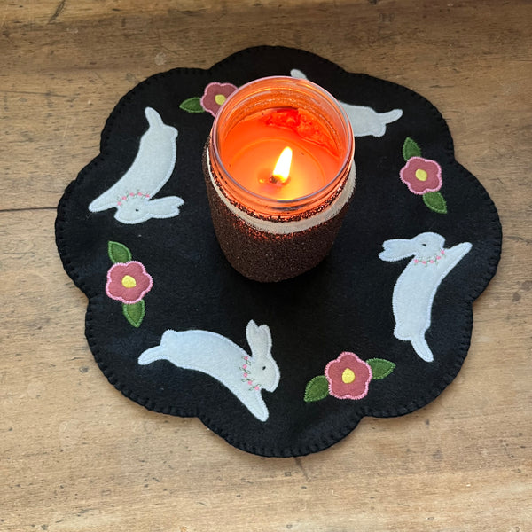 an in the hoop embroidery design of a candle mat with bunnies and flowers by snugglepuppyappique.com