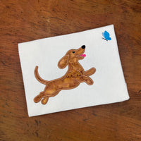 An applique of a playful dachshund chasing a butterfly in 6 sizes by snugglepuppyapplique.com