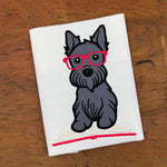 An appliqué of a Scottish Terrier with  his paws on an open book wearing glasses by snugglepuppyapplique.com