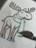 Cutting bobbin thread to release loop fringe of appliqué moose wearing a scarf