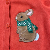 An applique of a cottontail rabbit standing on his back legs wearing a scarf with 3 dimensional fringe by snugglepuppyapplique.com