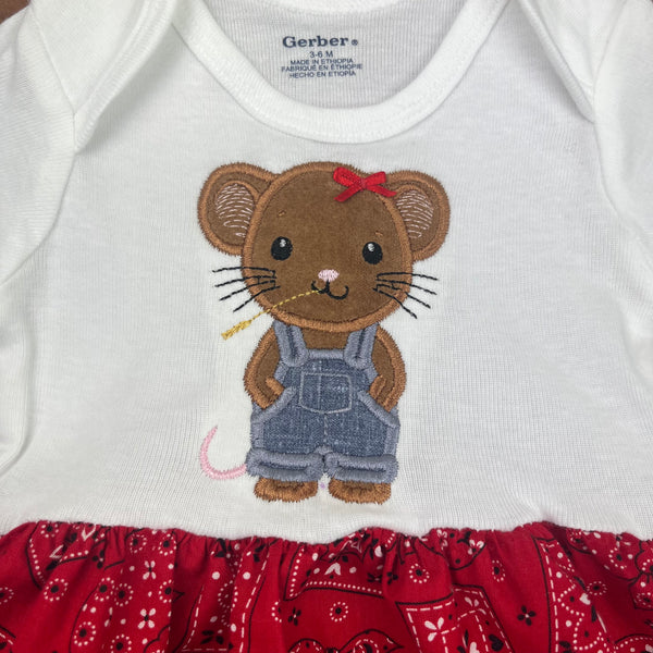 An applique of a little mouse wearing overalls and chewing on a stock of wheat by Snugglepuppyapplique.com
