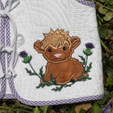 An applique of a highland calf lying among thistles with 3D fringe by snugglepuppyapplique.com