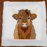 A patchwork applique of a Highland Cow by snugglepuppyapplique.com
