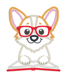 An appliqué of a corgi wearing glasses with his paws on an open book by snugglepuppyapplique.com