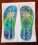 An applique of flip-flops with a daisy embroidered  on them.