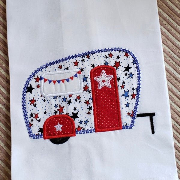 An applique of a camper with pennant flags across the windown  and a five pointed star on the door and fender by snugglepuppyapplque.com