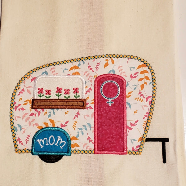 An applique of a camper with the female symbol on the door, "mom" on the fender and flowers in a window box by snugglepuppyapplique.com