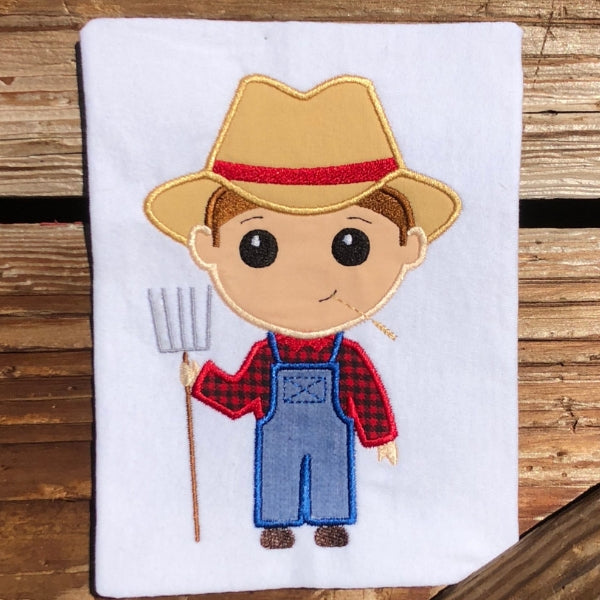 Farmer boy applique embroidery design, boy is holding pitchfork, has straw in his mouth and wearing overalls and a hat