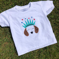 An applique of dachshund ears, nose and closed eyes wearing a statue of liberty crown with embroided stars above, by snugglepuppyapplique.com