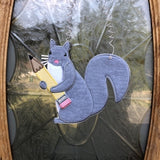An in the hoop squirrel holding a pencil door hanger embroidery design by www.snugglepuppyapplique.com