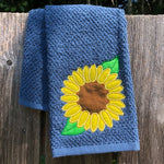 An applique of a sunflower with two leaves by snugglepuppyapplique.com