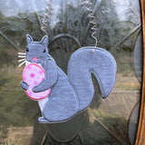 An in the hoop squirrel holding an easter egg door hanger embroidery design by www.snugglepuppyapplique.com