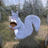 An in the hoop squirrel holding an acorn door hanger embroidery design by www.snugglepuppyapplique.com