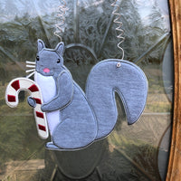 An in the hoop Squirrel holding a candy cane door hanger embroidery design by www.snugglepuppyapplique.com