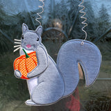 An in the hoop squirrel holding a pumpkin door hanger embroidery design by www.snugglepuppyapplique.com