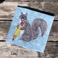 An applique of a squirrel holding a pencil and wearing glasses by snugglepuppyapplique.com