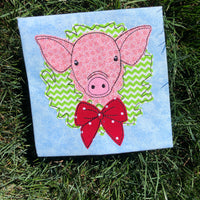 A bean stitch applique of a pig with his head through a Christmas wreath by snugglepuppyapplique.com