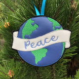 An ornament of the earth with a banner and "peace" embroidered on it. by snugglepuppyapplique.com
