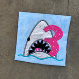 An applique of a shark biting the number 3 by snugglepuppyapplique.com