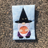 An applique of a gnome in a witch's hat holding a pumpkin by snugglepuppyapplique.com