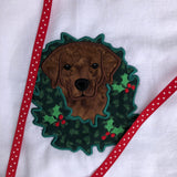 An applique of a Labrador with its head through a Christmas wreath by snugglepuppyapplique.com