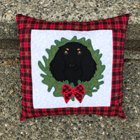 An applique of a long haired dachshund with it's head through a christmas wreath by snugglepuppyapplique.com