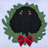 An applique of a long haired dachshund with it's head through a christmas wreath by snugglepuppyapplique.com