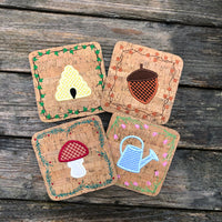 Four in the hoop Coasters one of a watering can with a tulip border, one of a bee hive with an ivy border, one of an acorn with a fall leave border and one of a mushroom with an evergreen border by snugglepuppyapplique.com