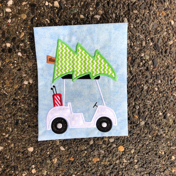 An applique of a Golf cart with a Christmas tree on top by snugglepuppyapplique.com