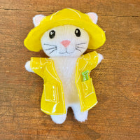 In the hoop kitten stuffy wearing a raincoat and hat embroidery design by snugglepuppyapplique.com